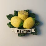 Front view of the France Menton Lemons fridge magnet, featuring three yellow lemons and green leaves.