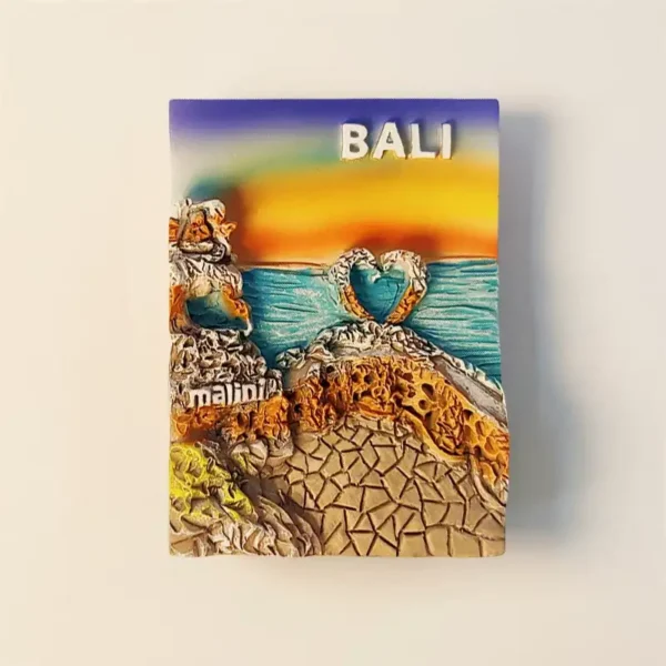 Front view of a colorful 3D Bali Uluwatu Lover's Cliff fridge magnet featuring a sunset, heart-shaped waves, and "Malini" restaurant text.