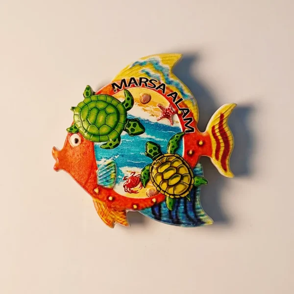Front view of a vibrant Marsa Alam Red Sea sea turtles fridge magnet, shaped like a fish, showing two green sea turtles, a crab, and seashells on a beach and ocean background.