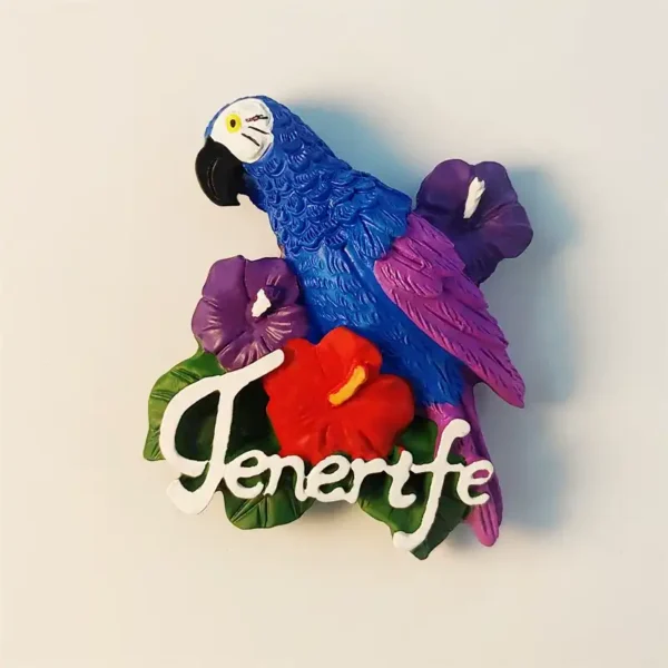 Close-up front view of a vibrant blue and purple parrot fridge magnet with red and purple hibiscus flowers and "Tenerife" script.