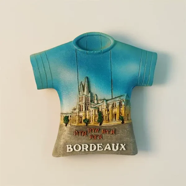 Front view of Bordeaux Cathédrale Saint-André T-shirt shaped souvenir fridge magnet, vibrant blue sky, detailed cathedral facade, "BORDEAUX" at base.