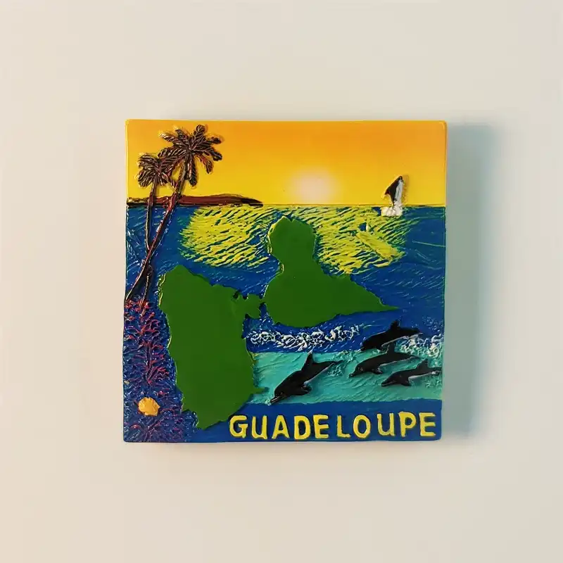 Front view of a Guadeloupe sunset seascape fridge magnet featuring palm trees, dolphins, sailboat, and the island outline.