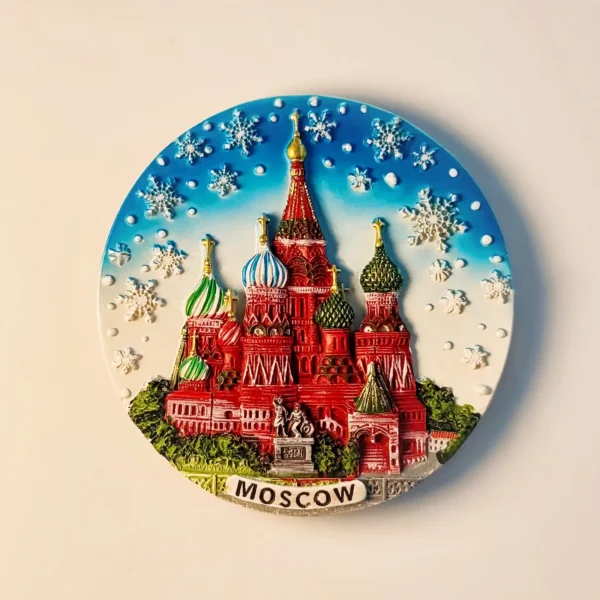 A circular 3D relief fridge magnet featuring the colorful domes of Saint Basil's Cathedral in Moscow under a snowy winter sky.
