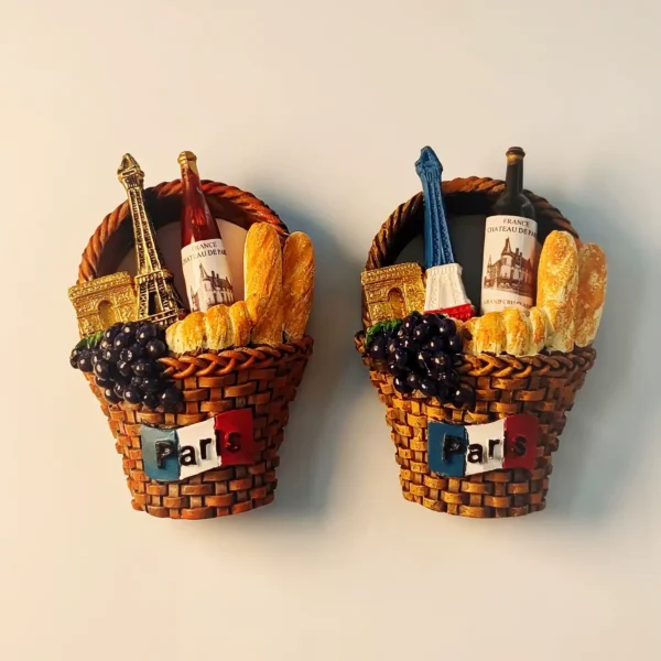 Front view of a vibrant 3D Paris souvenir fridge magnet featuring Eiffel Tower, Arc de Triomphe, wine, baguettes, and grapes in a brown picnic basket.
