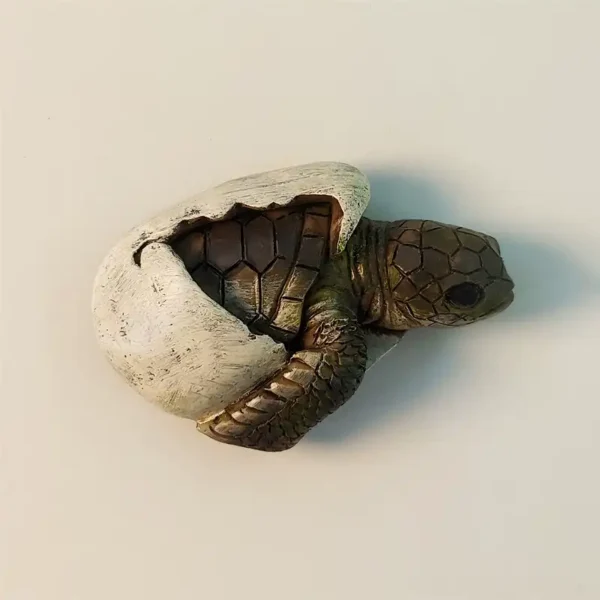 Front view of a detailed 3D baby sea turtle hatching from an egg fridge magnet, capturing the moment of birth and new life.