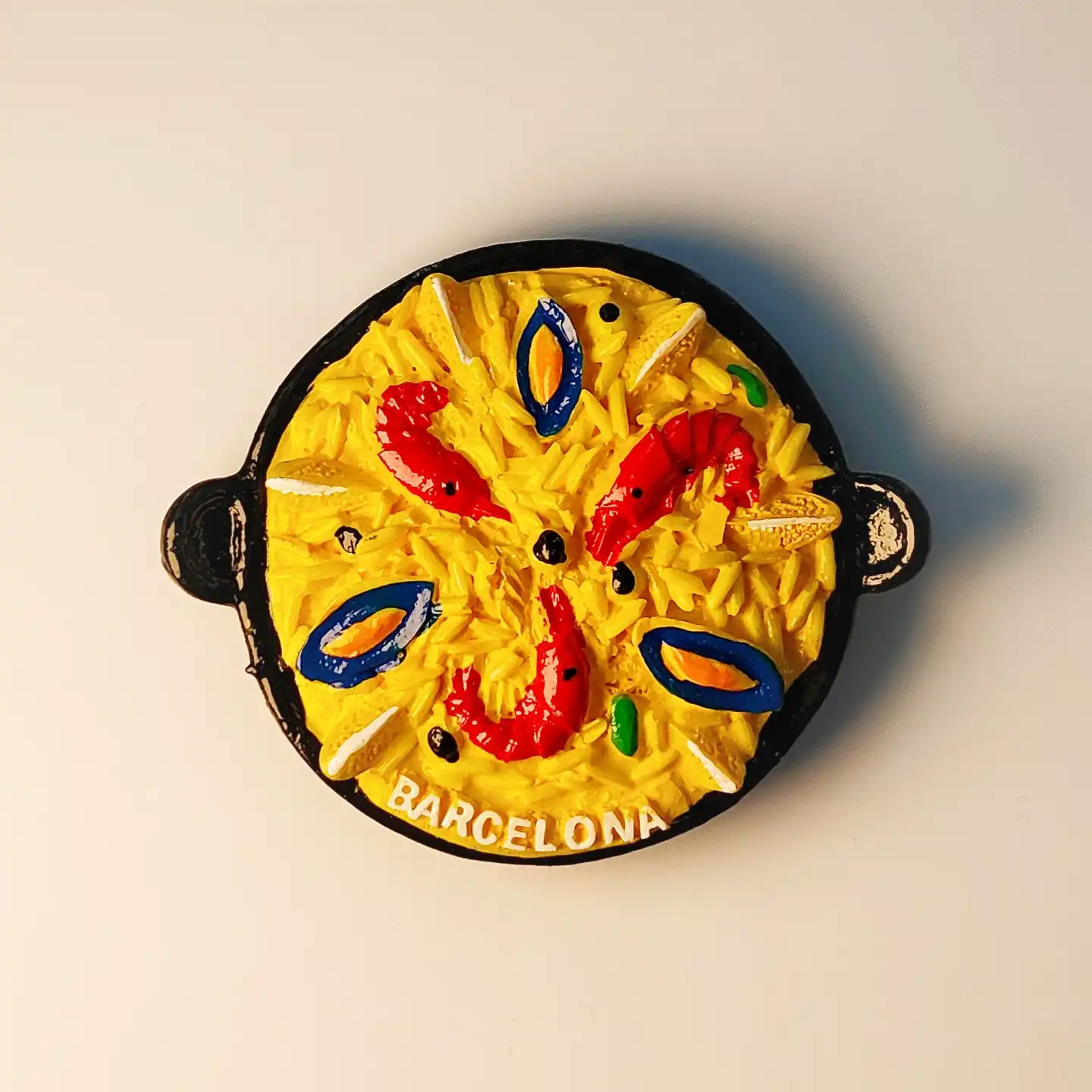 barcelona-seafood-paella-fridge-magnet-front 3D resin fridge magnet of Spanish seafood paella in a black pan with Barcelona text.