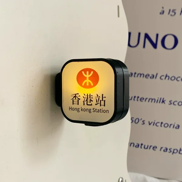 Light-up Hong Kong Station MTR fridge magnet glowing on white wall with orange logo and Chinese text