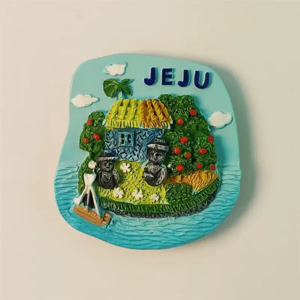 Front view of a colorful Jeju Island fridge magnet featuring a traditional thatched house and Dol Hareubang statues.