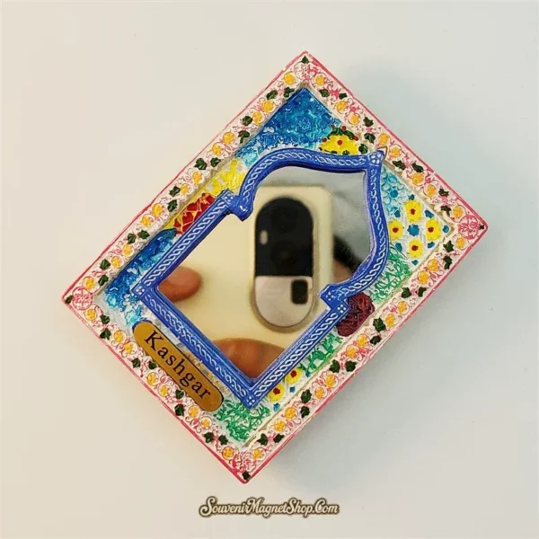 Angled view of Kashgar souvenir fridge magnet showing blue arch mirror frame and hand-painted floral border