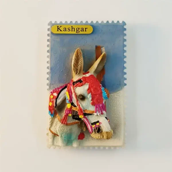 Front view of Kashgar souvenir fridge magnet in stamp shape with 3D white donkey head wearing colorful Uyghur festive decorations