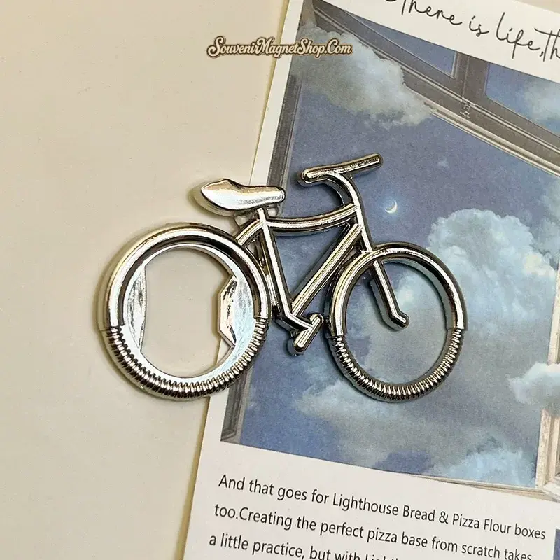 Close-up of silver retro bicycle bottle opener fridge magnet on lifestyle art book
