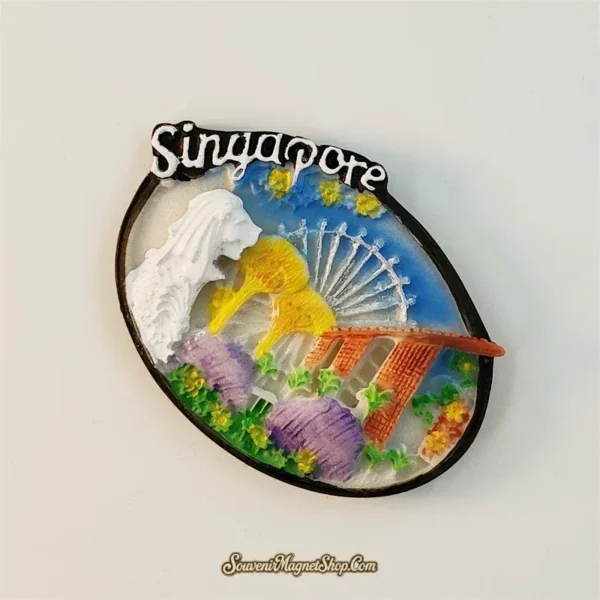 Angled view of Singapore multi-landmark fridge magnet showing 3D relief depth of Merlion and Marina Bay Sands on oval base