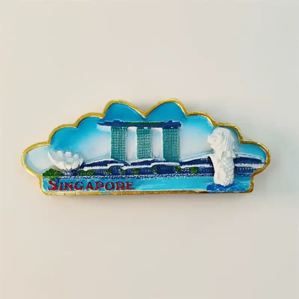 Front view of Singapore souvenir fridge magnet in wide cloud shape with gold border showing 3D Marina Bay Sands towers and Merlion