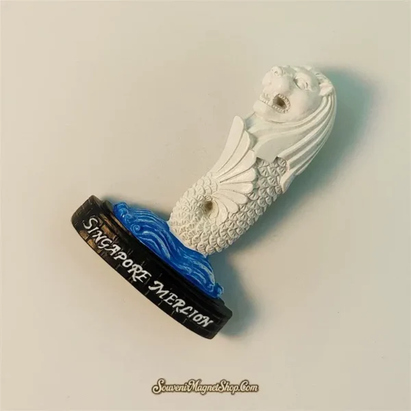 Angled side view of Singapore Merlion souvenir magnet highlighting detailed fish scale body texture and painted blue wave base