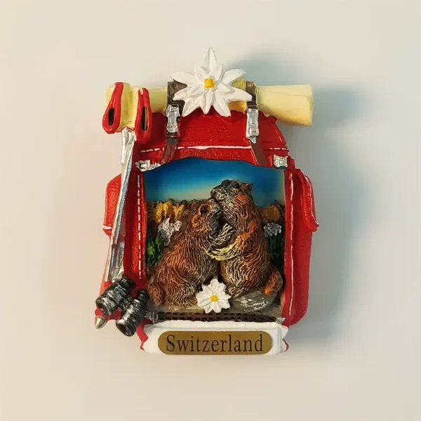 Front view of a 3D hand-painted Switzerland Alps marmot hiking backpack fridge magnet featuring two marmots, edelweiss, and hiking gear.