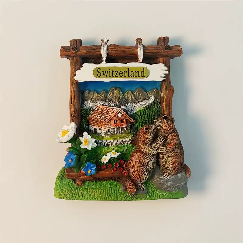 switzerland-swiss-alps-marmots-fridge-magnet-front Front view of the Switzerland Swiss Alps marmots fridge magnet, featuring a hand-painted 3D alpine scene with a chalet and a pair of playful marmots.