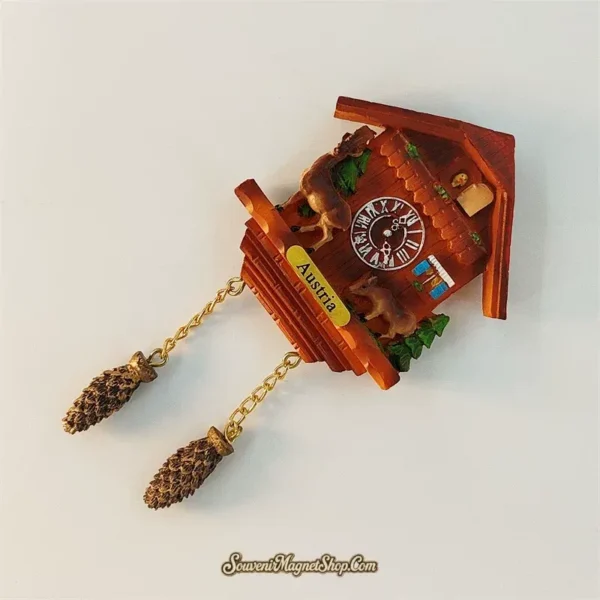 Austria Alpine cuckoo clock souvenir magnet angled view with hand-painted chalet, deer and dangling pinecone weights
