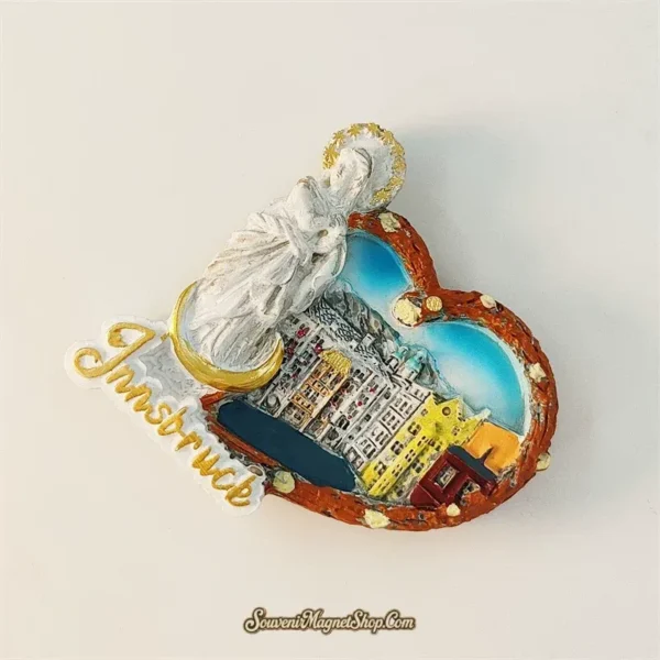 Angled view of Innsbruck pretzel heart fridge magnet showing 3D relief depth of Old Town cityscape and Madonna statue