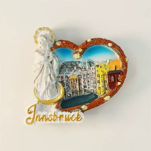Front view of Austria Innsbruck souvenir fridge magnet with pretzel heart frame showing Old Town colorful facades Alpine mountains and white Madonna statue with gold halo