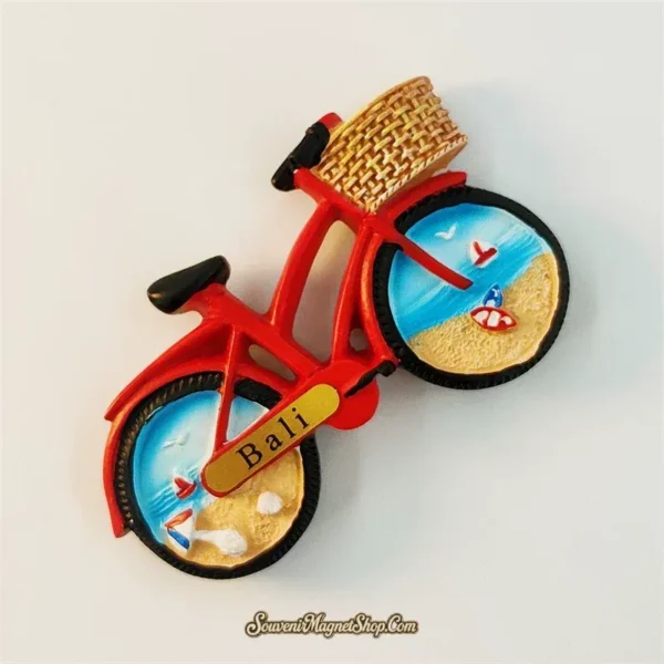 Angled view of Bali red bicycle souvenir magnet showing 3D wicker basket and beach-painted wheels