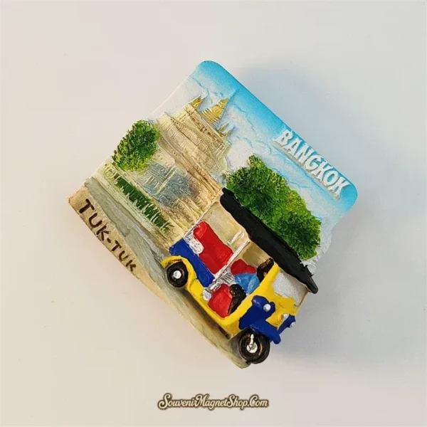 Angled left view of Bangkok tuk-tuk souvenir magnet showing 3D street scene with temple and green trees