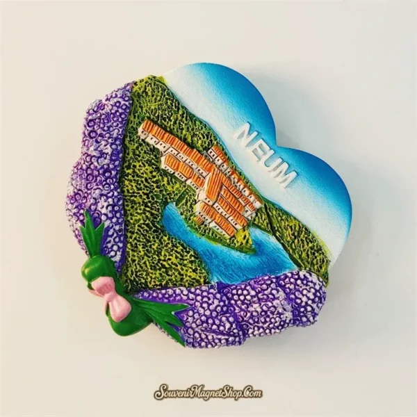 Bosnia Neum souvenir fridge magnet angled left view revealing 3D relief depth of heart shape with lavender bunches, pink bow and coastal town aerial scene