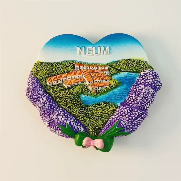 Bosnia Neum heart-shaped fridge magnet front view showing coastal town with orange rooftops, green hills, blue sea, purple lavender flowers and pink bow at base