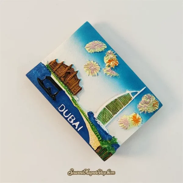 Angled view of hand-painted Dubai magnet showing 3D relief Burj Al Arab and Atlantis The Palm