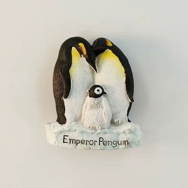 Emperor penguin family fridge magnet front view with two adult penguins and fluffy chick on snowy base