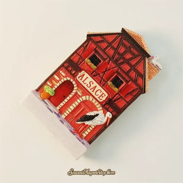 Angled left view of Alsace half-timbered house souvenir magnet showing 3D depth and stork detail