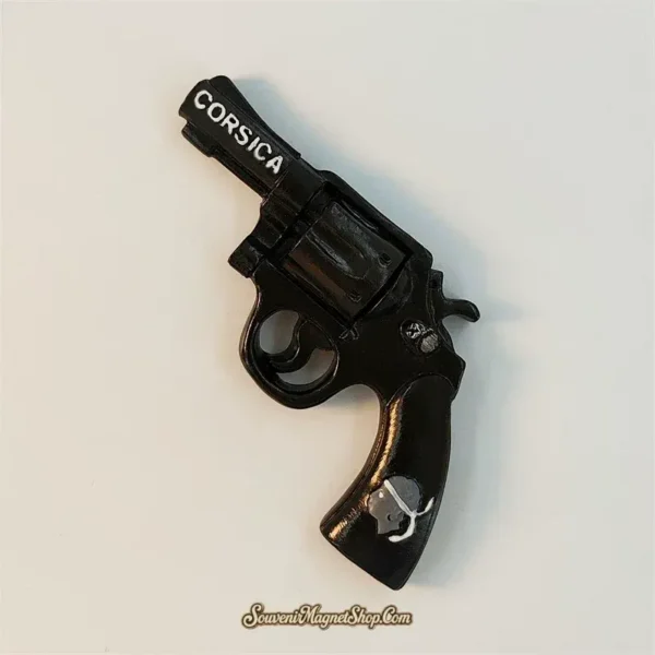 Angled view of black Corsica revolver souvenir fridge magnet showing 3D sculpted cylinder, trigger and hand-painted details