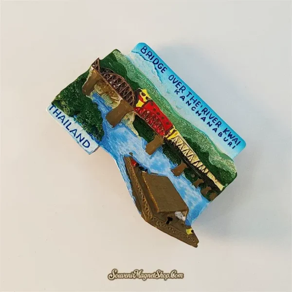 Angled left view of Kanchanaburi River Kwai bridge souvenir magnet showing 3D trusses train and mountain backdrop