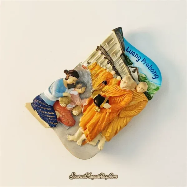Luang Prabang monks souvenir magnet left angle showing 3D relief depth of alms giving scene with colonial building background