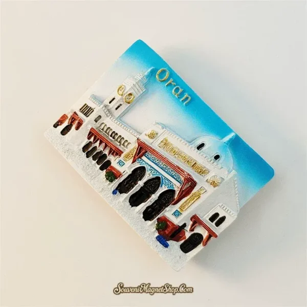 Angled view of Oran mosque souvenir magnet showing hand-painted 3D relief with red awnings and gold details