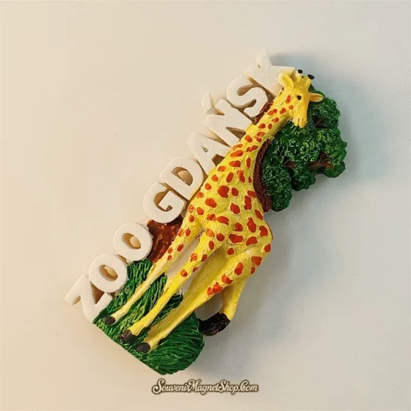 Gdańsk Zoo souvenir fridge magnet angled left view revealing 3D depth of yellow giraffe figure green canopy trees and bold white ZOO GDANSK vertical lettering