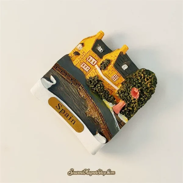 Angled left view of Spain village souvenir magnet showing 3D cottage bridge and garden details