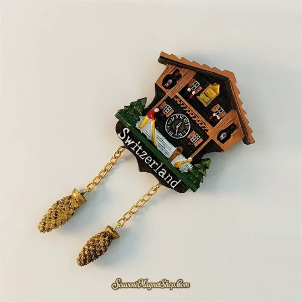 Left-angle view of Switzerland cuckoo clock souvenir magnet showing hand-painted chalet detail and gold pine cone pendants