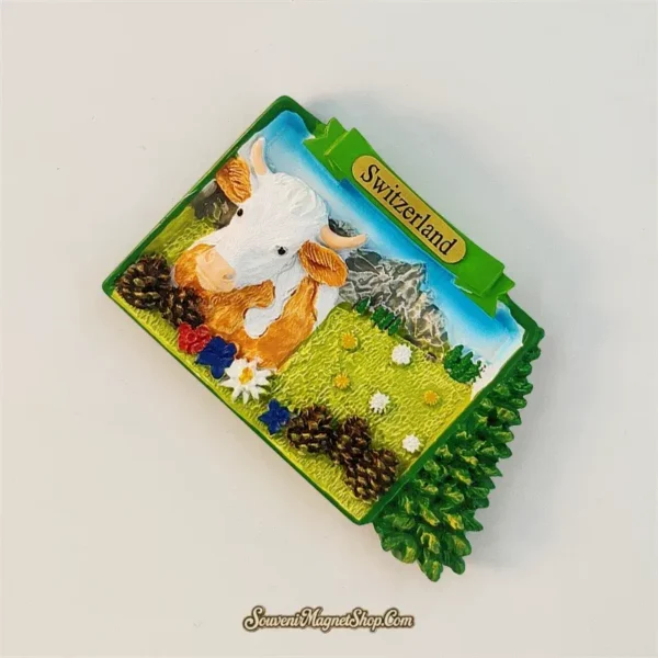 Angled view of Switzerland souvenir fridge magnet showing 3D Swiss cow and alpine meadow detail