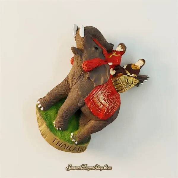 Thailand elephant souvenir magnet back angle showing red and gold ceremonial saddle and two seated figures