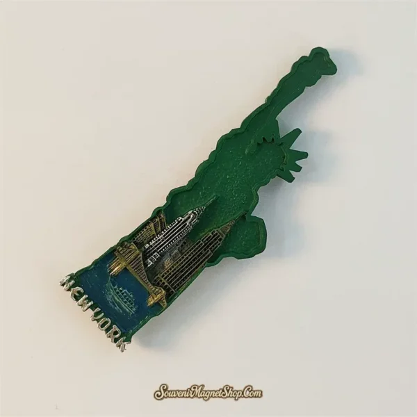Side angle of New York Statue of Liberty souvenir magnet revealing 3D relief of Manhattan skyline and bridge