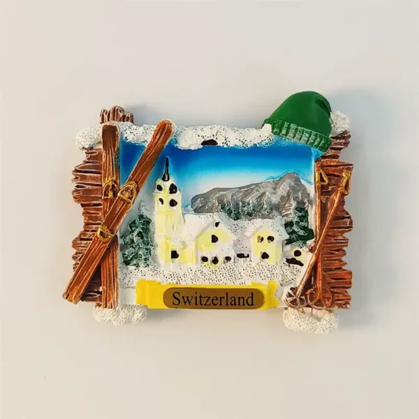 Switzerland Jungfrau fridge magnet front view with snow village, church steeple, crossed skis and green knit ski cap