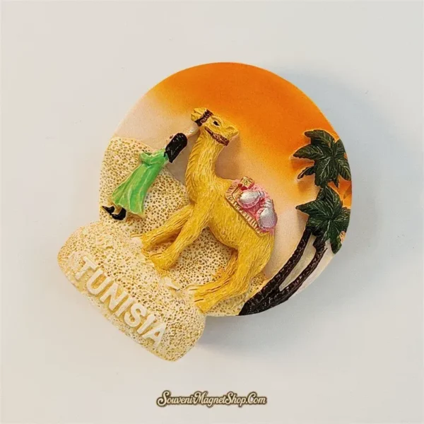 Angled view of Tunisia camel souvenir magnet showing 3D palm tree and orange desert sunset