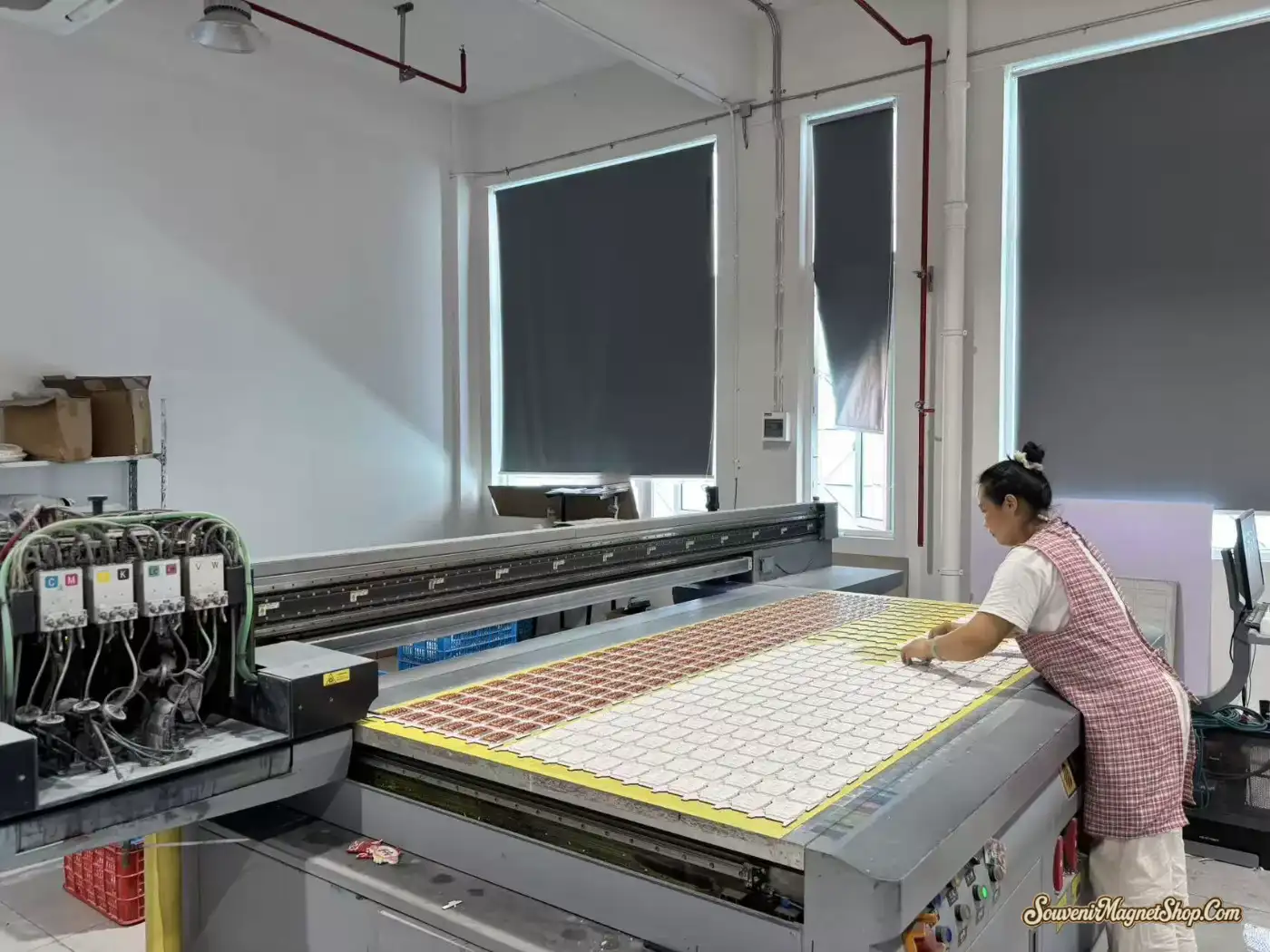 Industrial UV flatbed printer printing souvenir fridge magnet designs in batch — full CMYK + white ink, in our Quanzhou color workshop.