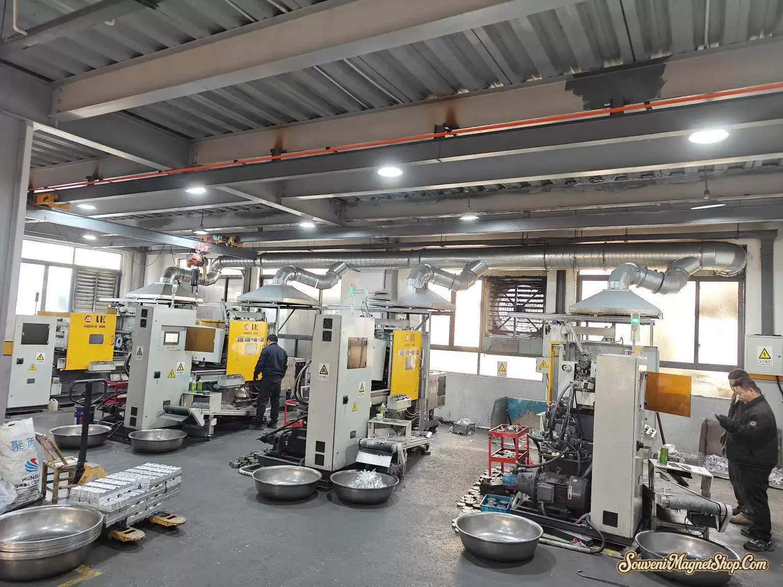 Industrial LK die-casting machines with exhaust extraction producing zinc-alloy bases for premium metal souvenir magnets — one of 13 active production lines.