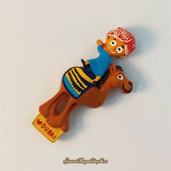 Dubai souvenir magnet of cartoon boy on a camel with striped saddle shown at an angle, 3D hand-painted detail