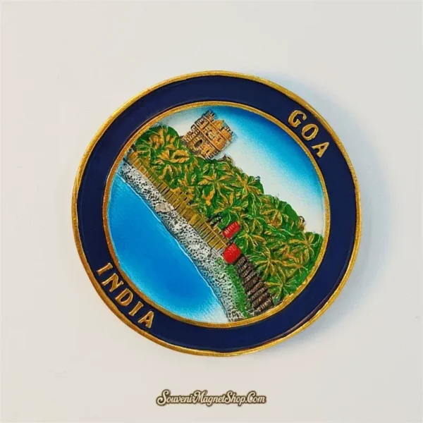 Angled view of round Goa India souvenir magnet showing 3D coastal scene with palms and fort