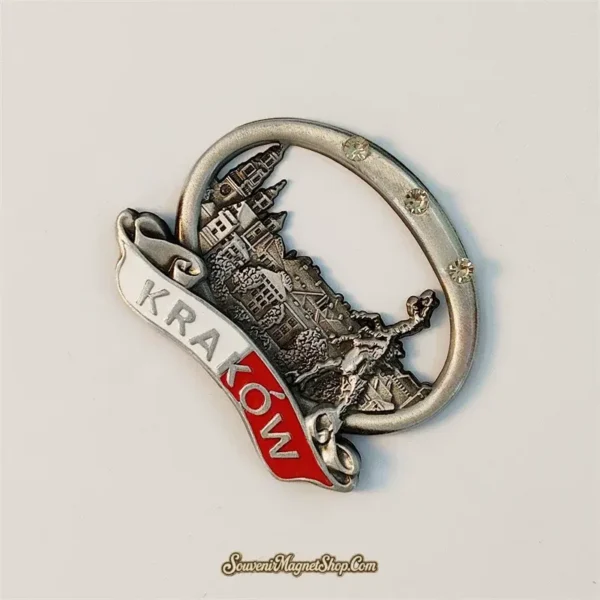 Angled view of a Krakow souvenir fridge magnet in antique silver metal showing the embossed Wawel skyline and sculpted figure