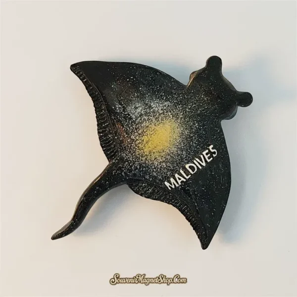 Maldives manta ray souvenir magnet shown at an angle with speckled ocean finish and golden glow