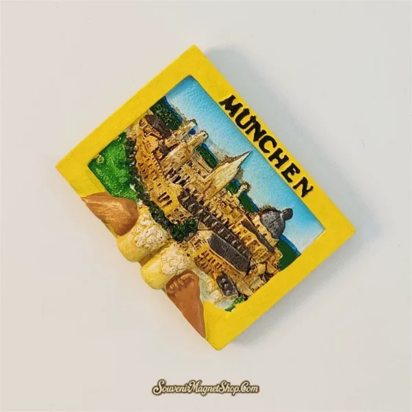 Angled Munich souvenir magnet showing 3D golden cityscape and frothy beer mugs toasting