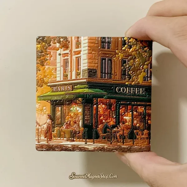 Hand holding Paris coffee cafe souvenir fridge magnet showing its compact size